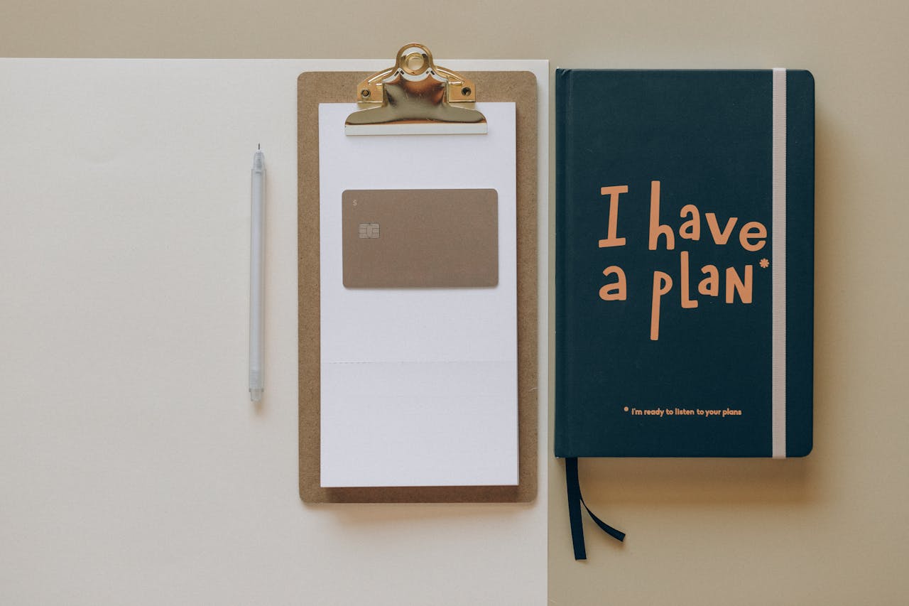 A minimalist office setup featuring a planner, clipboard, card, and pen, perfect for planning and organization.